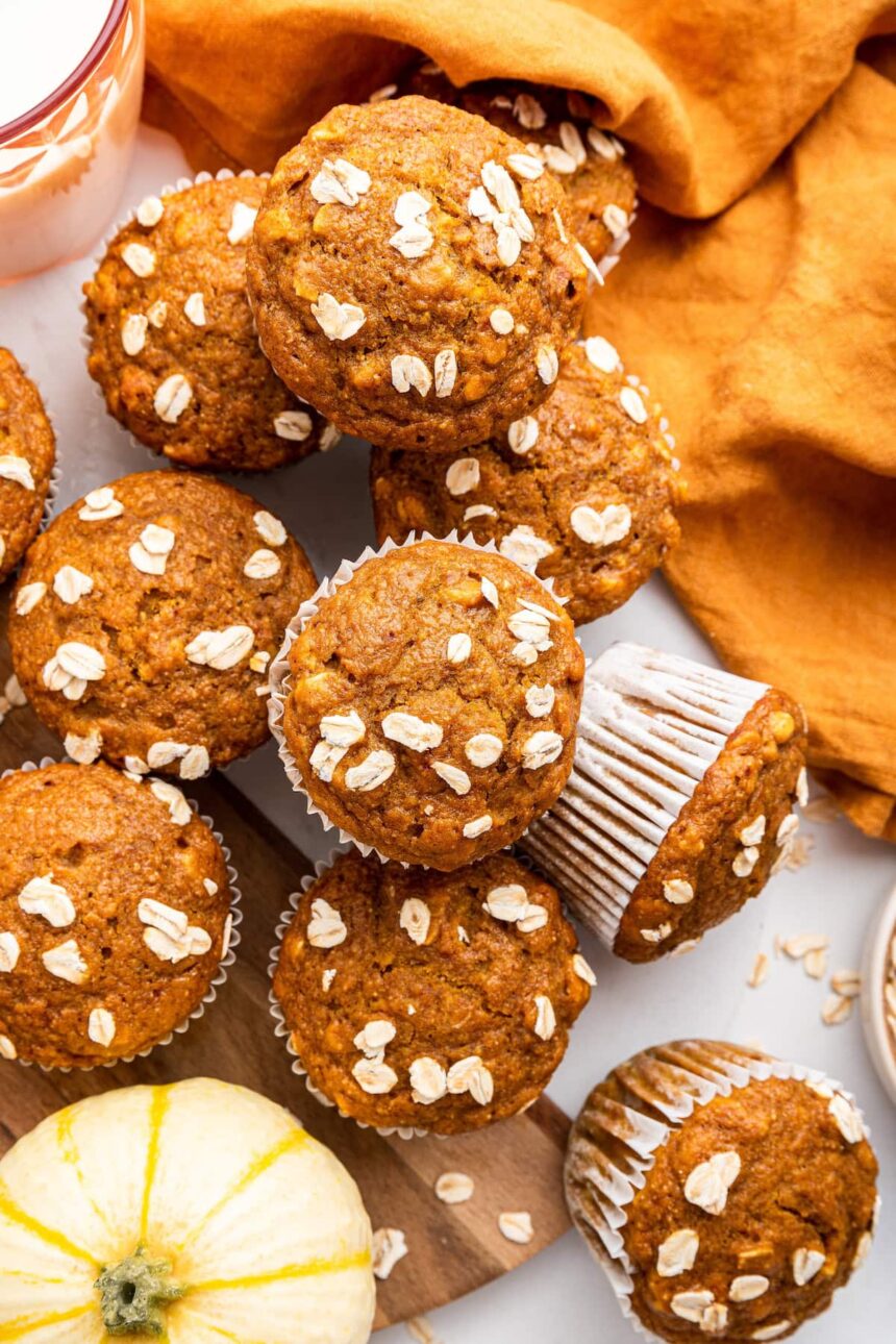 Multiple pumpkin muffins near one another with some stacked on top of others.