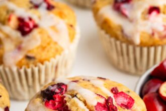 A cranberry orange muffin topped with a drizzle of an almond milk based glaze.