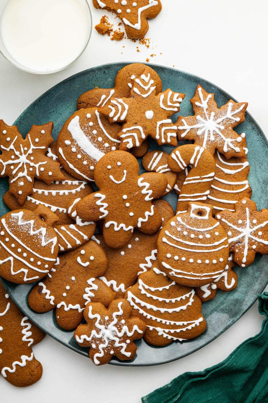 Multiple gingerbread cookies decorated with icing on a plate.