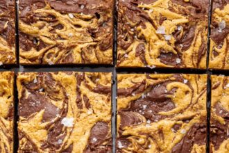 Peanut butter brownies cut into 16 squares. The brownies are topped with a peanut butter swirl and flaked sea salt.